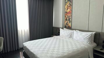 Una habitación de hotel con una cama grande, un cuadro en la pared y una ventana con cortinas.