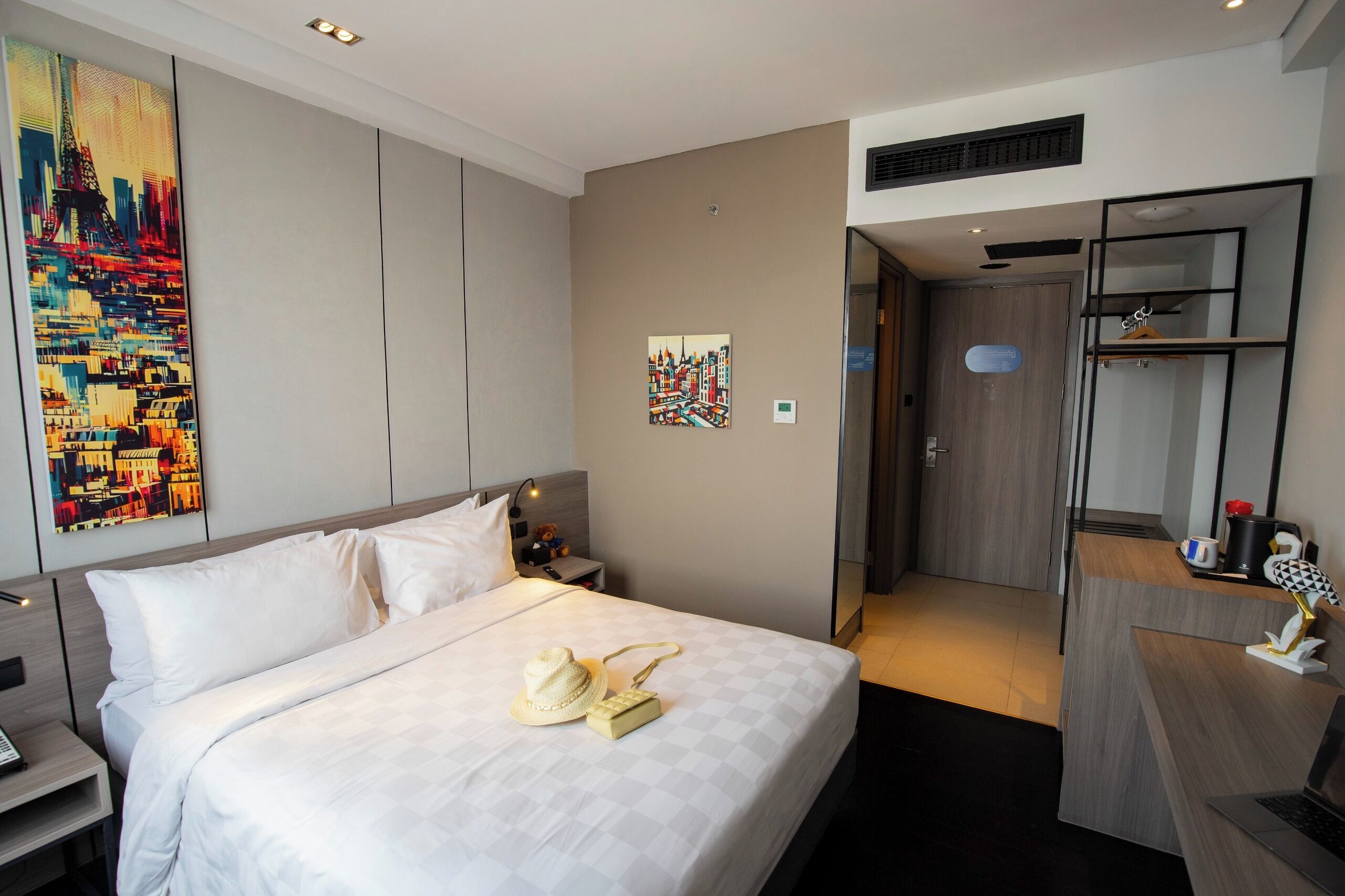 Una habitación de hotel con una cama grande, un escritorio, un espejo y obras de arte en las paredes.