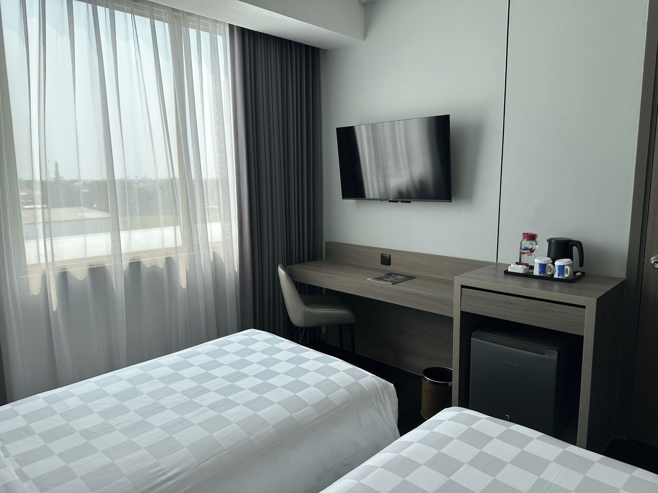 Habitación de hotel con dos camas, un escritorio con silla, televisión y minibar.