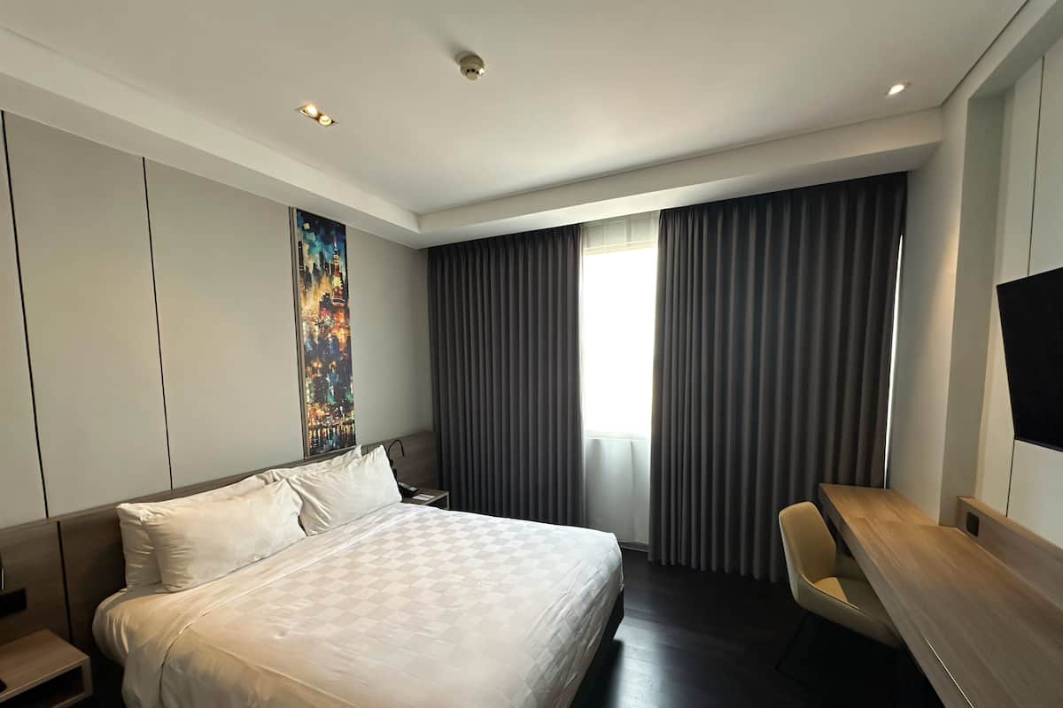 Une chambre d’hôtel moderne avec un grand lit, un bureau et un tableau au mur.