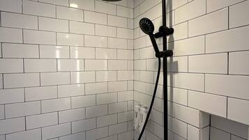 A shower with a handheld showerhead and a wall-mounted control.