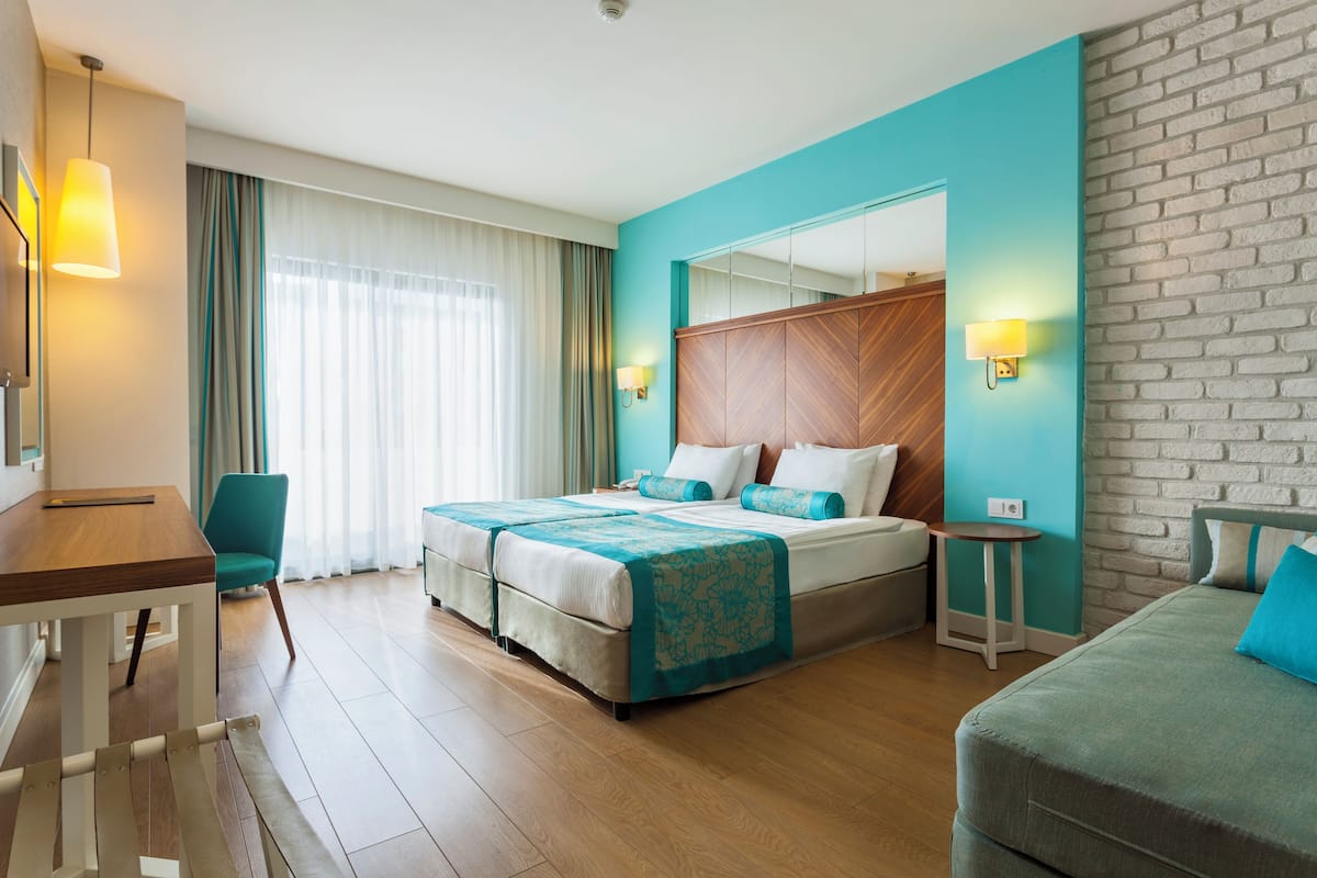 A hotel room with a bed, a desk, a chair, and a small table.