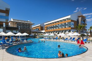 A swimming pool area with lounge chairs and umbrellas, surrounded by modern buildings with balconies. - Terrace Elite Resort - All Inclusive (Manavgat)