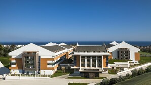 A modern hotel with multiple buildings, a central structure with large windows, and a view of the sea. - Terrace Elite Resort - All Inclusive (Manavgat)
