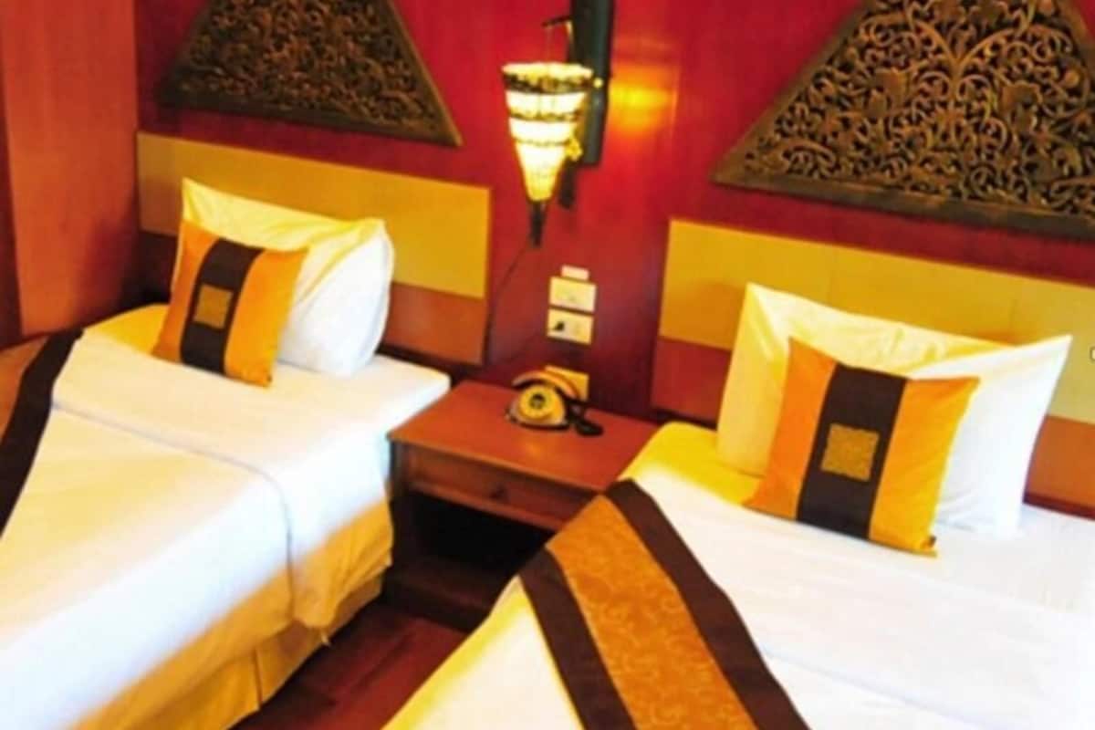 Habitación de hotel con dos camas, una mesita de noche con teléfono y paneles decorativos en la pared.
