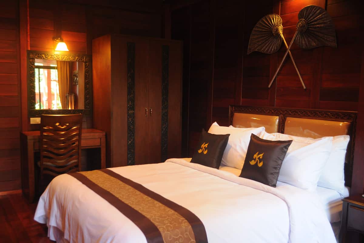 A hotel room with a large bed, a wooden wardrobe, a desk, and a mirror.