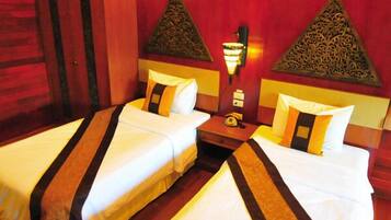 Habitación de hotel con dos camas, cada una con ropa blanca a rayas marrones, un armario de madera y paneles decorativos en la pared.