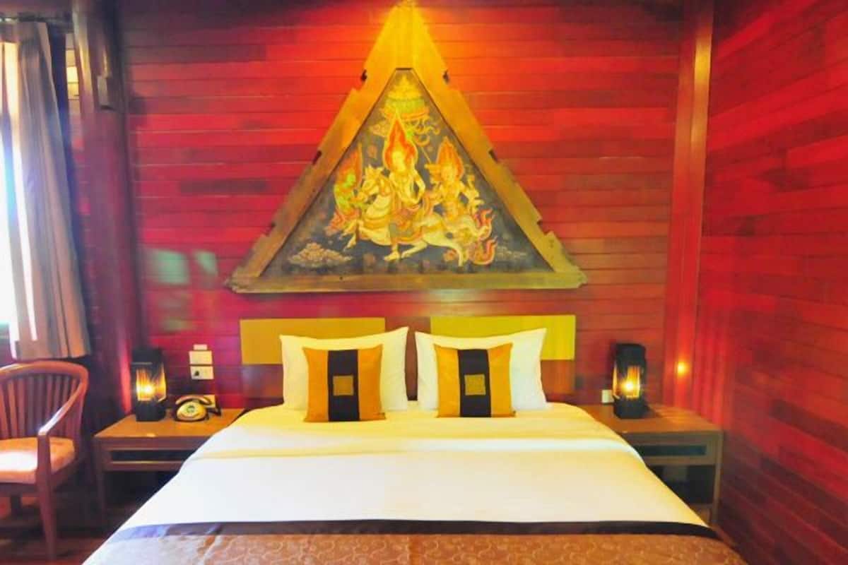 A hotel room with a bed, a nightstand, a chair, and a wall-mounted painting.