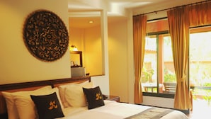 A hotel room with a large bed, a mirror, and a window with curtains. - Ruen Kanok Thai House (Hua Hin)