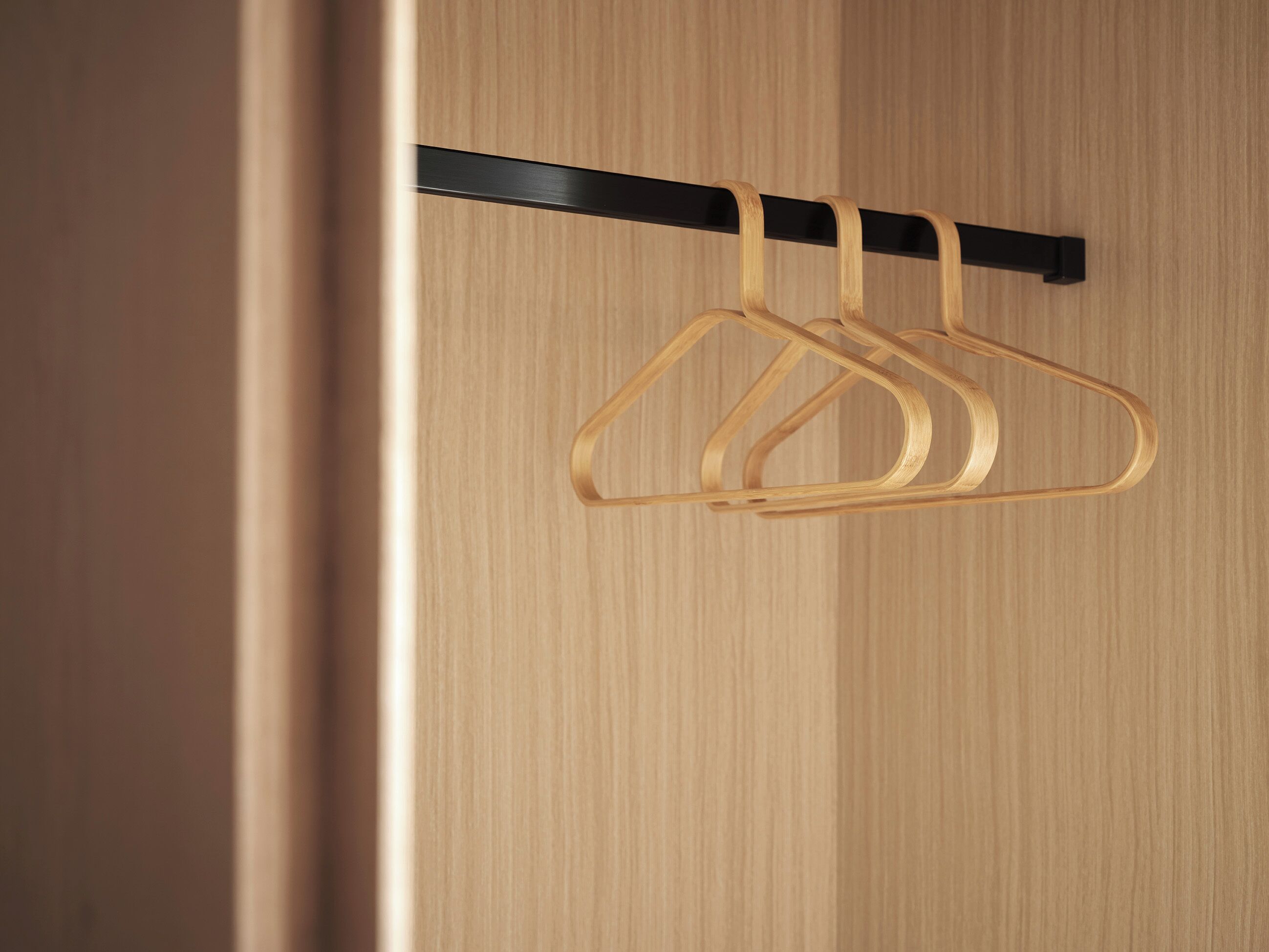 A wooden door with a black horizontal bar and two wooden hangers.
