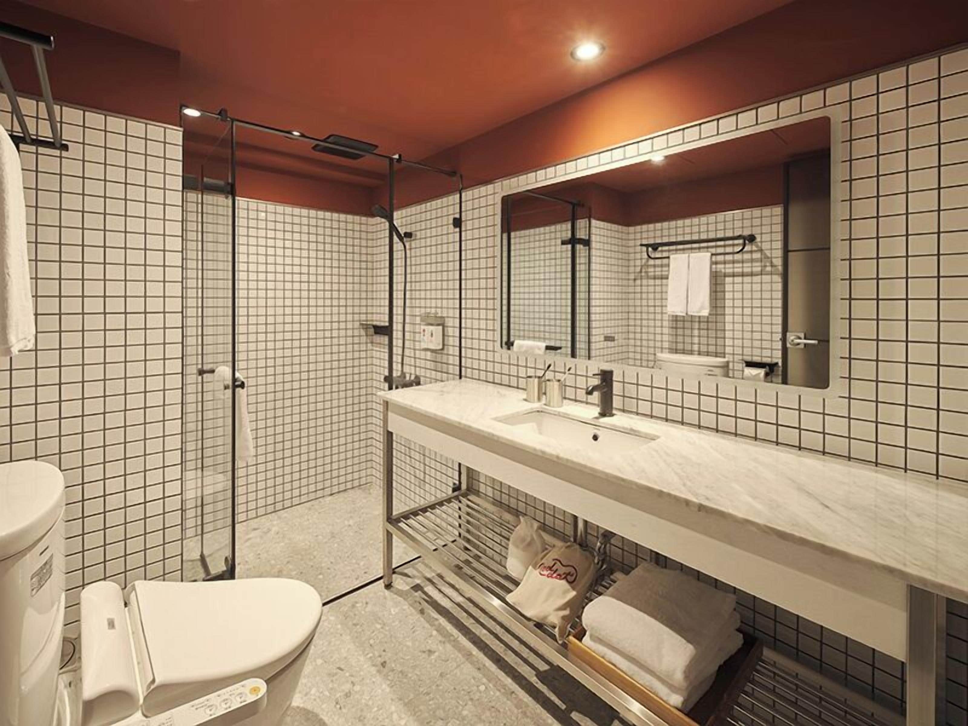 A modern bathroom with a large mirror, a sink, and a shower.
