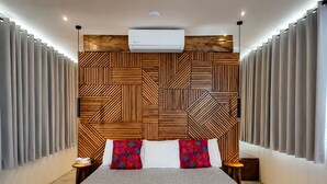 A modern bedroom with a geometric patterned headboard, a large bed with grey bedding, and grey curtains on the windows. - Hotel Casa del Sótano (Oaxaca)