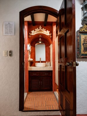 A bathroom with a wooden door, a mirror, a sink, and a towel rack. - Hotel Casa del Sótano (Oaxaca)