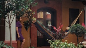 A person standing near a staircase with a hammock and plants. - Hotel Casa del Sótano (Oaxaca)