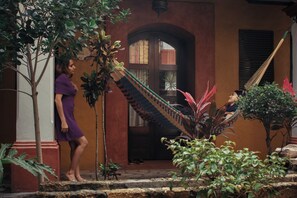 A person standing near a staircase with a hammock and plants. - Hotel Casa del Sótano (Oaxaca)