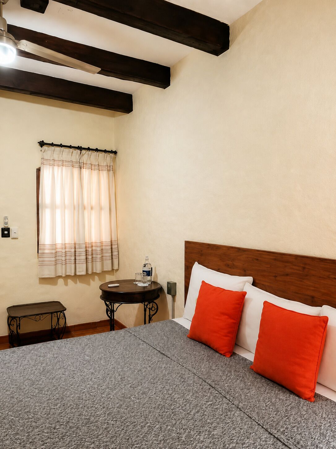 Une chambre à coucher avec un lit, une table de chevet, une petite table et une fenêtre avec des rideaux.