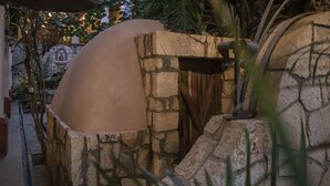 A stone oven structure with a dome roof, surrounded by stone walls and plants. - Hotel Casa del Sótano (Oaxaca)