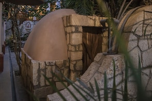 A stone oven structure with a dome roof, surrounded by stone walls and plants. - Hotel Casa del Sótano (Oaxaca)