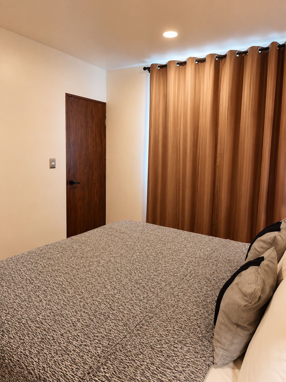 A bedroom with a bed, a door, and a curtain.
