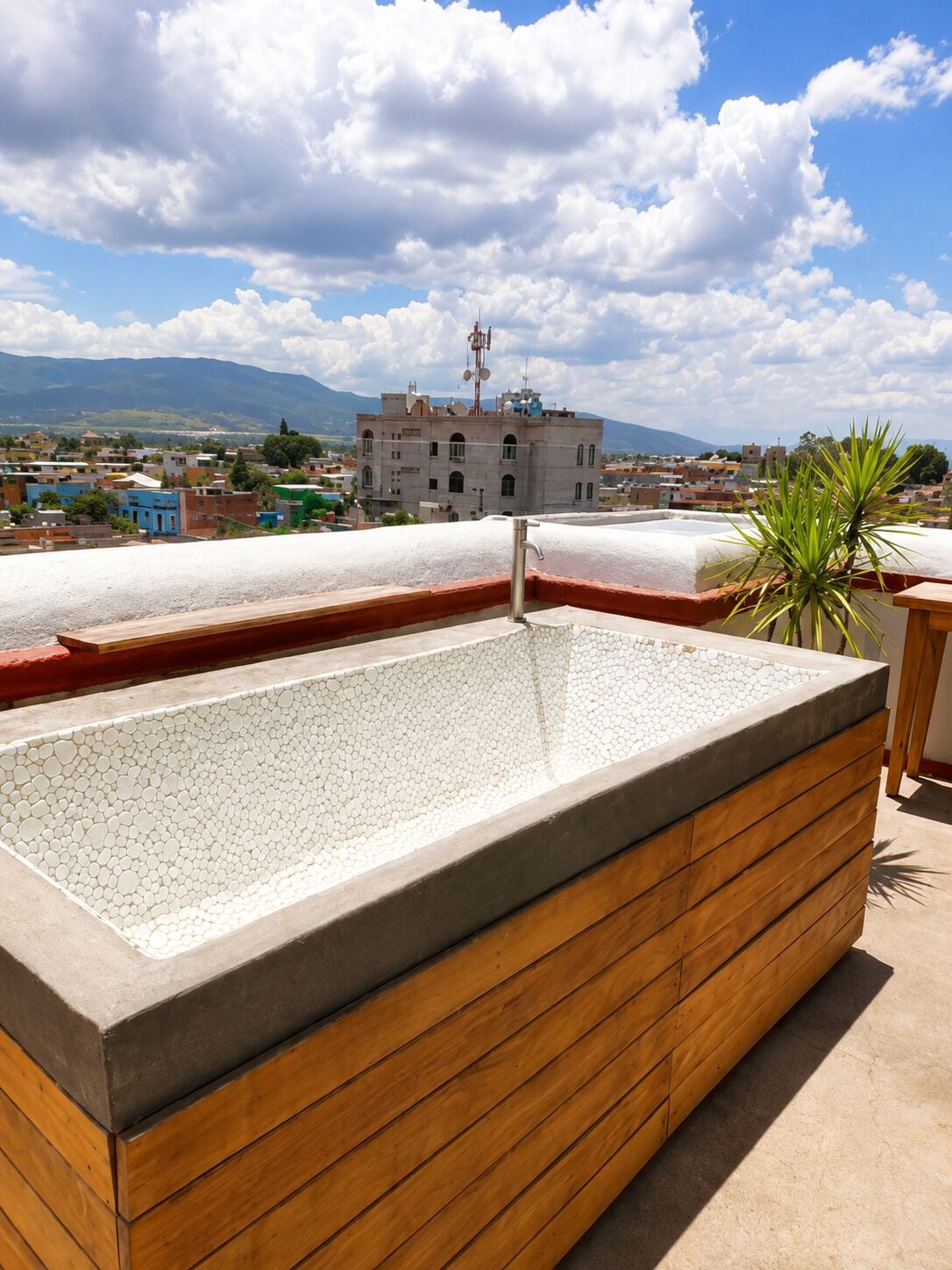 A rooftop pool with a clear view of a town and mountains in the background.