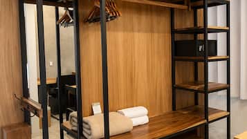 Un lit superposé avec une structure en bois et des étagères, un petit bureau et un porte-manteau mural.