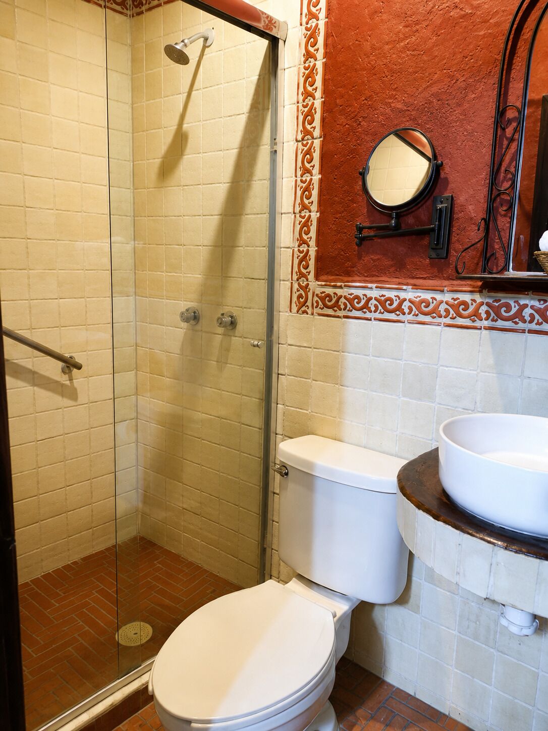 Een badkamer met een douchecabine van glas, een toilet en een wastafel met spiegel erboven.