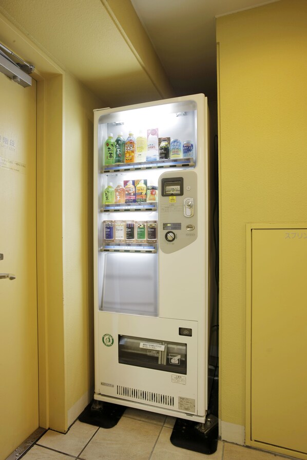 A vending machine in a narrow hallway with a yellow wall. - Hotel Lumiere Kasai (Tokyo)