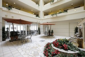 Un atrium à plusieurs niveaux, doté d’un sol en pierre, d’un espace extérieur aménagé pour s’asseoir et de plantes en pot.
