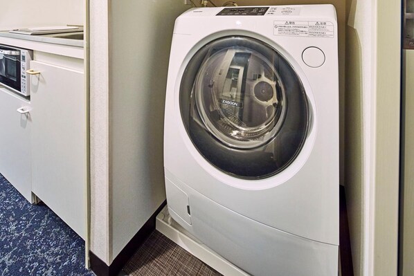 Une machine à laver à chargement frontal dans une chambre d’hôtel.