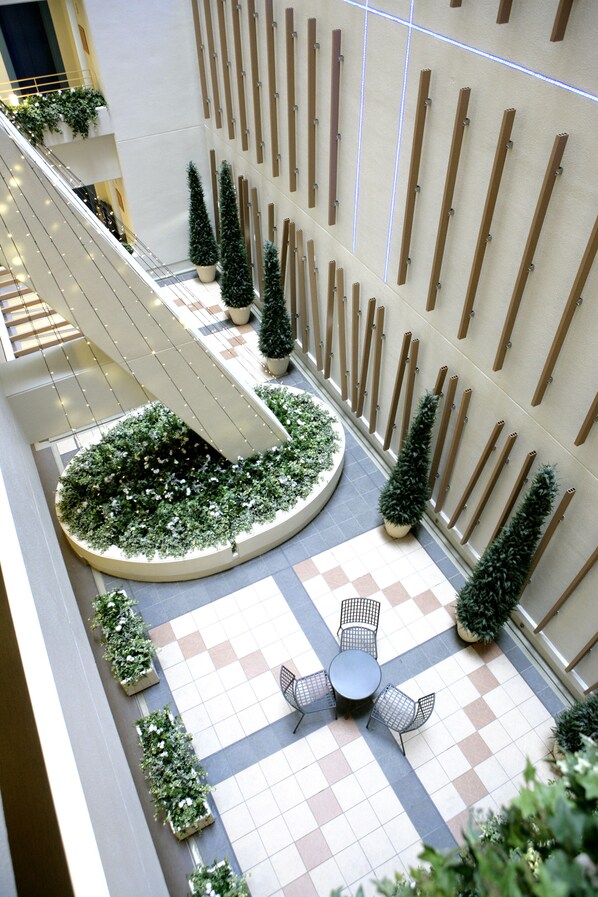 A multi-level atrium with a central staircase, potted plants, and a checkered floor pattern.