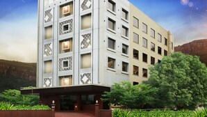 A multi-story hotel named Raj Park with a modern architectural design, featuring a prominent entrance and surrounding greenery.