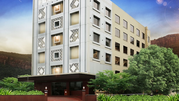 Un hotel de varios pisos llamado Raj Park, con un diseño arquitectónico moderno, una entrada destacada y zonas verdes circundantes.