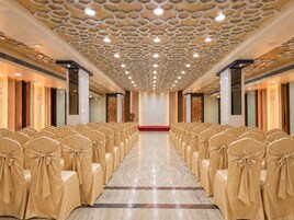 Un salón de conferencias con hileras de sillas, techo estampado y alfombra roja.
