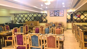 A dining area with multiple tables and chairs, some with cushioned seats.
