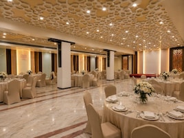 A banquet hall with round tables, chairs, and a decorative ceiling.
