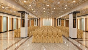 Un salón de conferencias con filas de sillas, una alfombra roja y un techo con diseño.