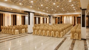 Un salón de conferencias con filas de sillas, techo estampado y suelo de mármol.