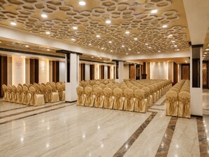 Un salón de conferencias con filas de sillas, techo estampado y suelo de mármol.