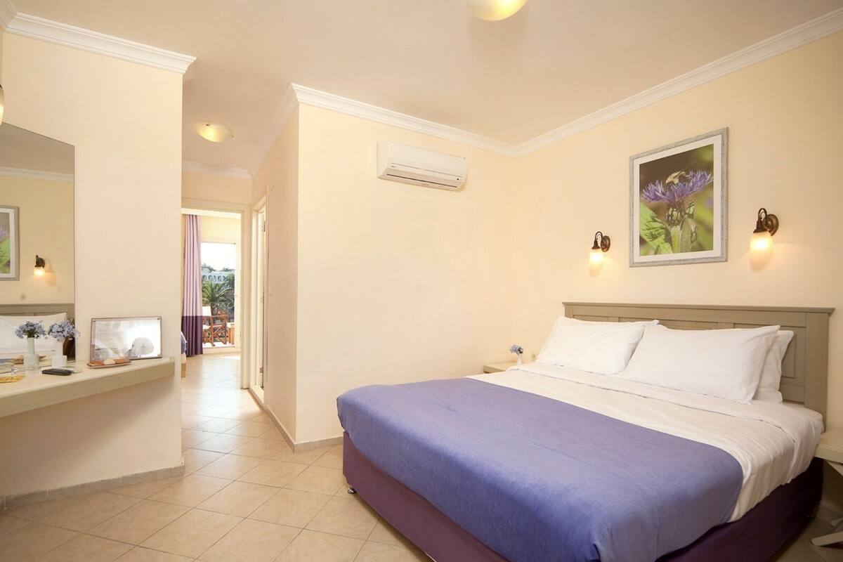 A hotel room with a bed, a desk, a chair, and a window.
