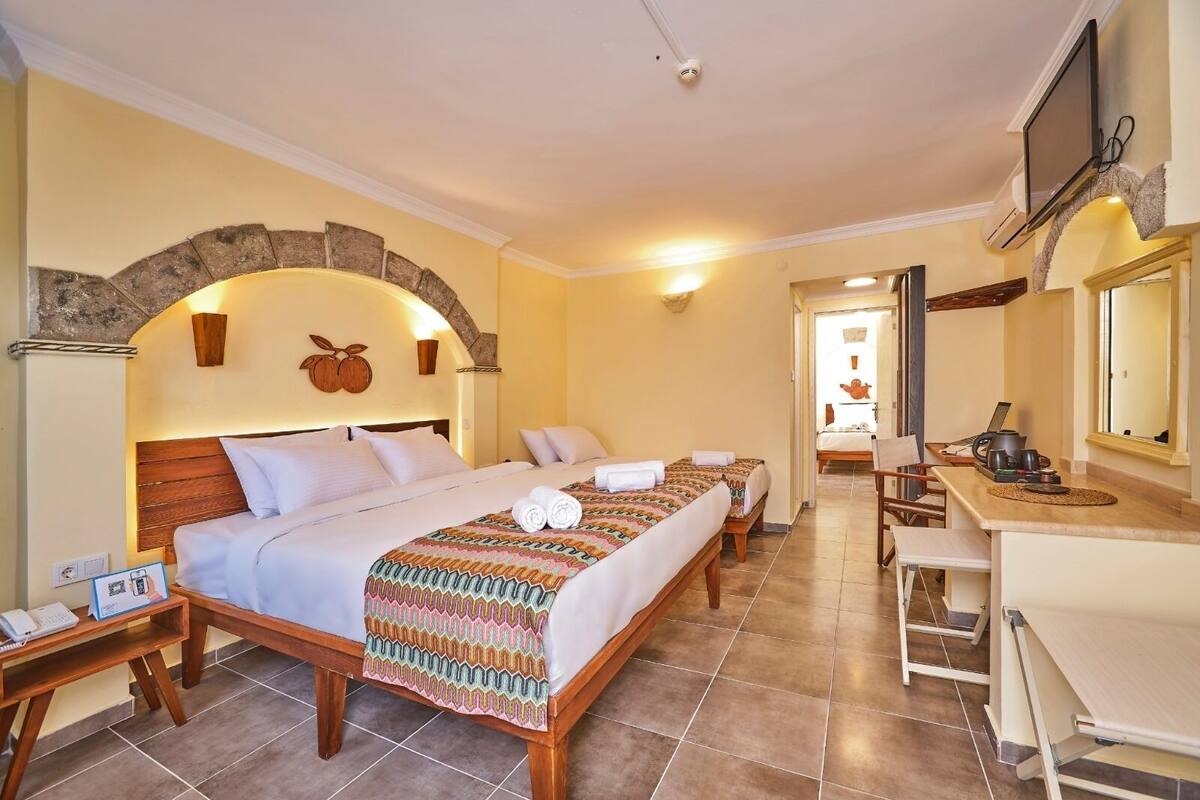 A hotel room with a large bed, a desk, and a TV.