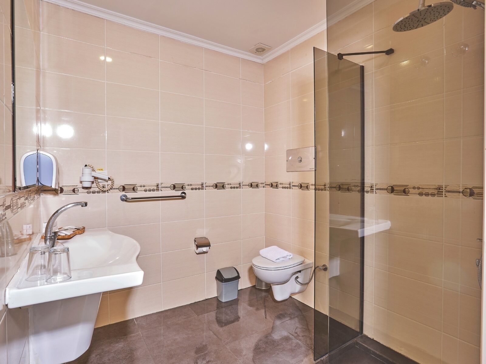 Ein modernes Badezimmer mit Duschkabine aus Glas, einem weißen Waschbecken mit Spiegel und einer Toilette mit Bidetfunktion.