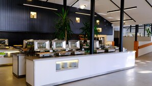 A buffet setup with multiple serving stations, a central plant, and a modern interior design.