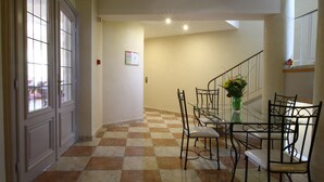 A dining area with a checkered floor, a glass table, metal chairs, and a vase with flowers. - Champ'Alsace Centre (Haguenau)
