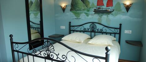 Un dormitorio con cama, espejo en la pared y un mural de un velero.