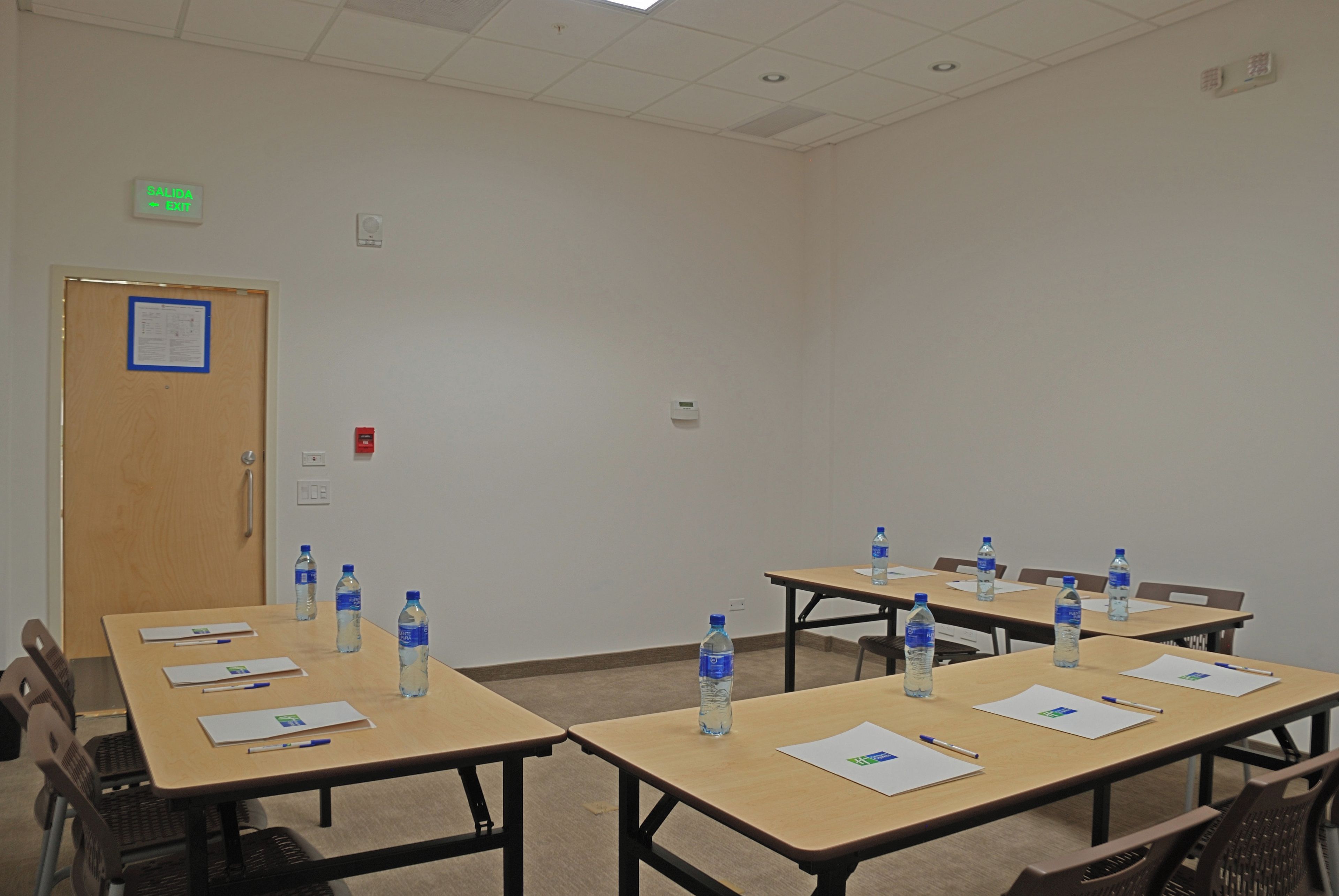 A conference room with tables, chairs, water bottles, and documents.