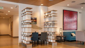 A modern interior with a wooden floor, a blue sofa, a grey chair, and a bookshelf unit. - Holiday Inn Express Managua by IHG (Managua)