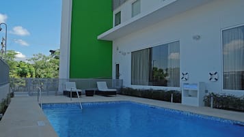 A swimming pool with lounge chairs and a lifebuoy on the wall.