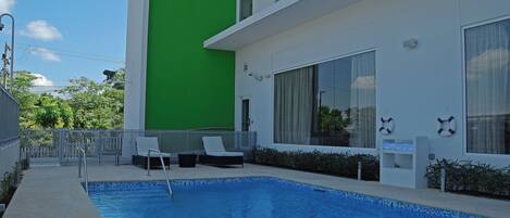 A swimming pool with lounge chairs and a lifebuoy on the wall.