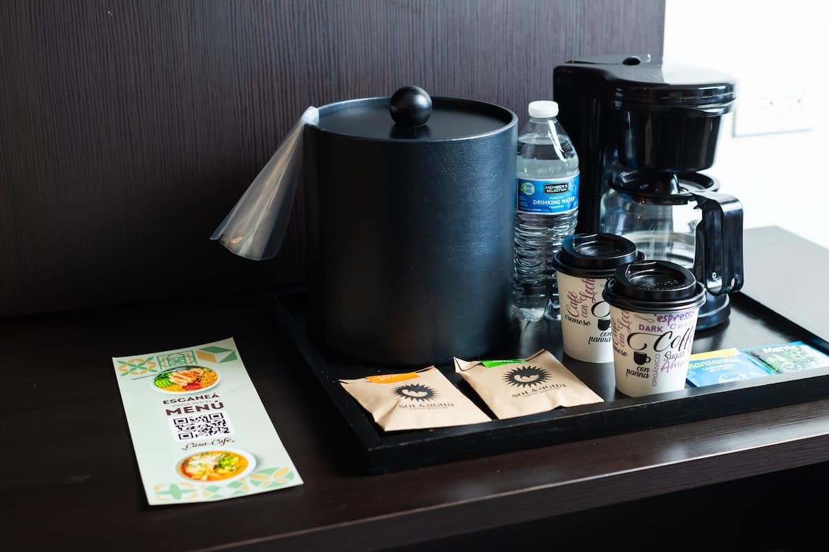 A tray with a coffee maker, water bottles, coffee cups, and a menu.