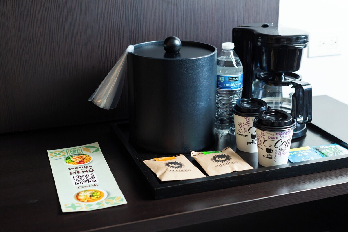 A tray with a coffee maker, water bottles, coffee cups, and a menu.